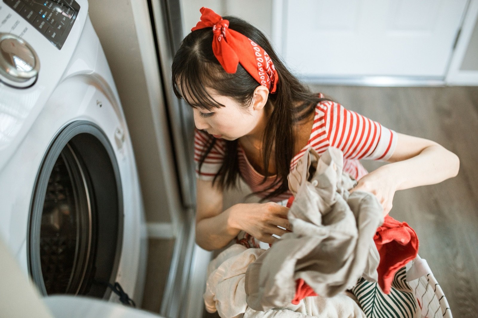 Person removing freshly washed laundry from a front-loading washer into a basket