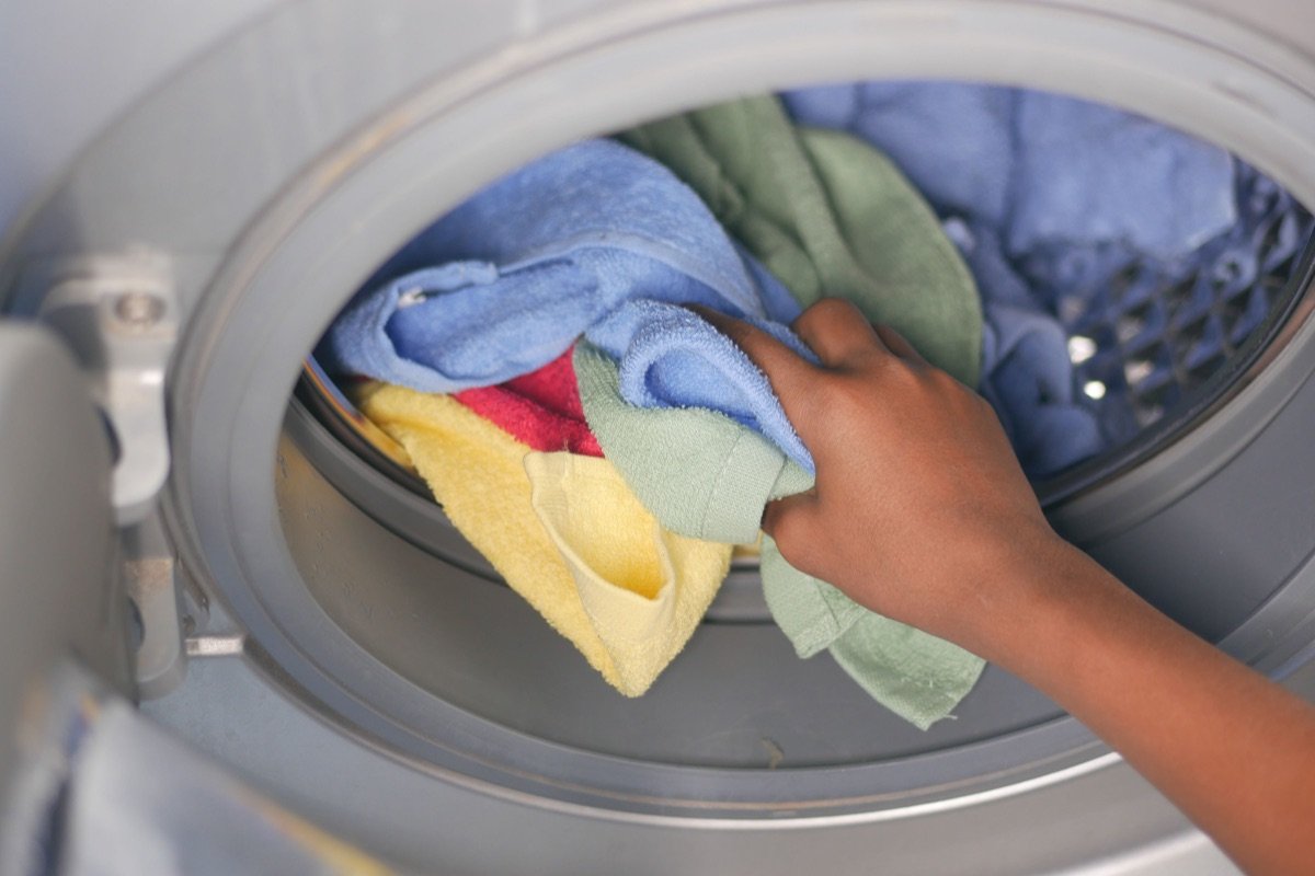 Hand loading light and dark towels into a front-loading washing machine