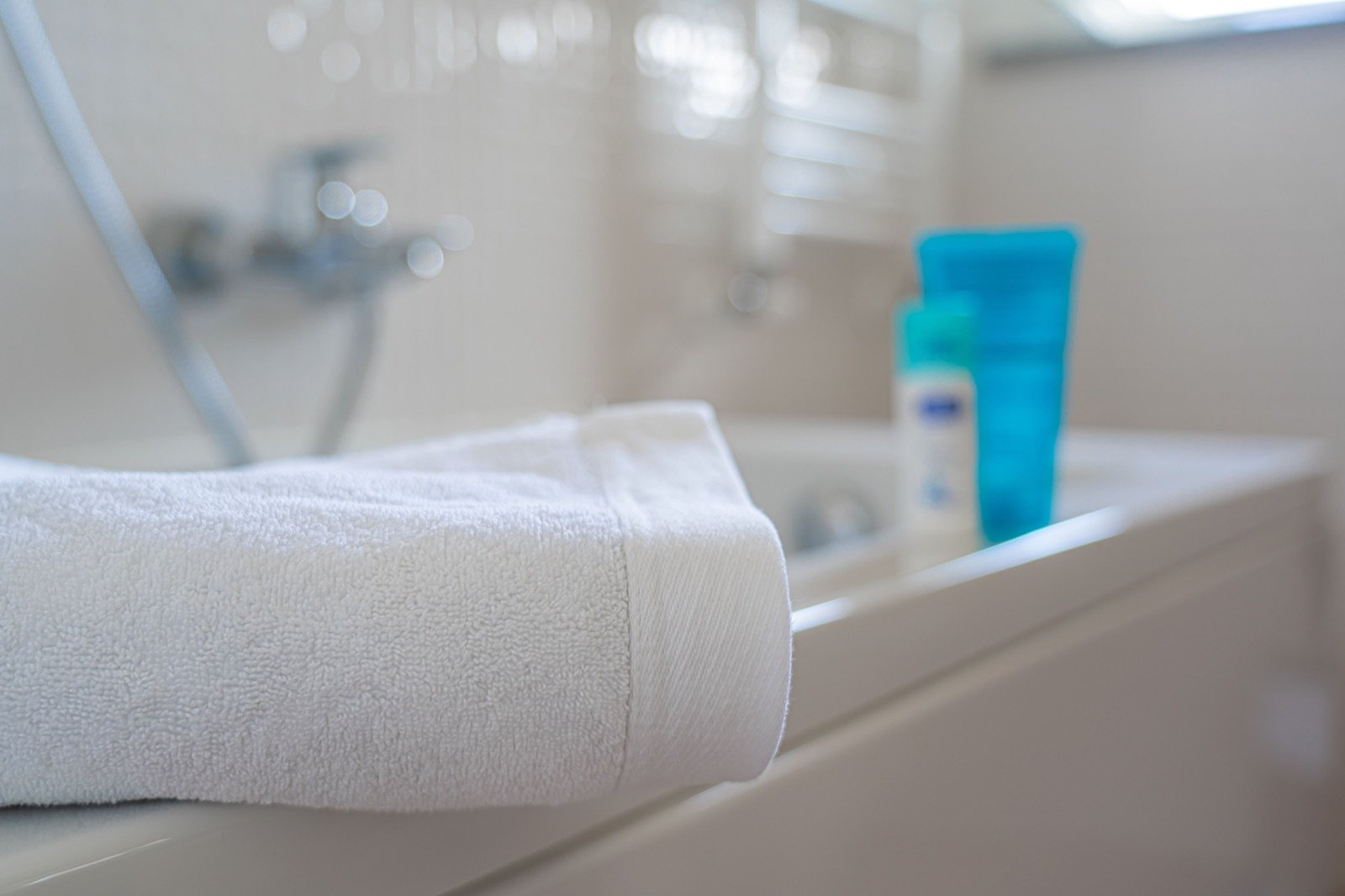 Folded white bath towel on the edge of a bathtub in a clean bathroom